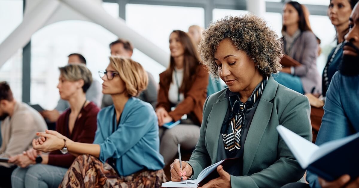 Sellers take notes while attending a session on sales skills.