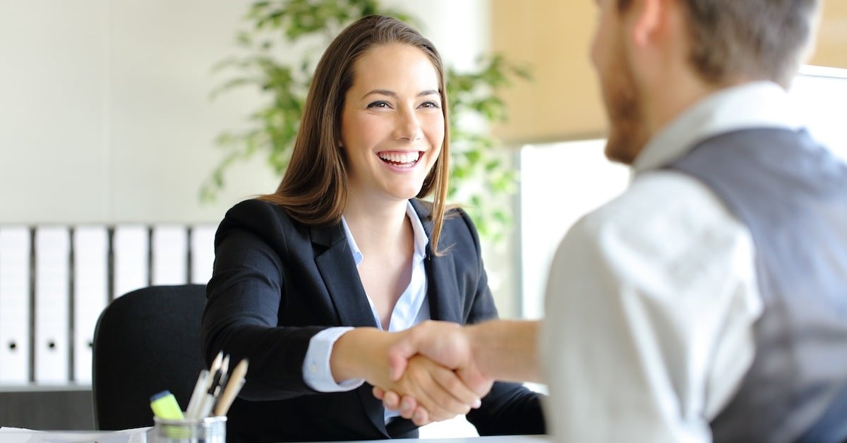 A seller greets a buyer with a handshake.